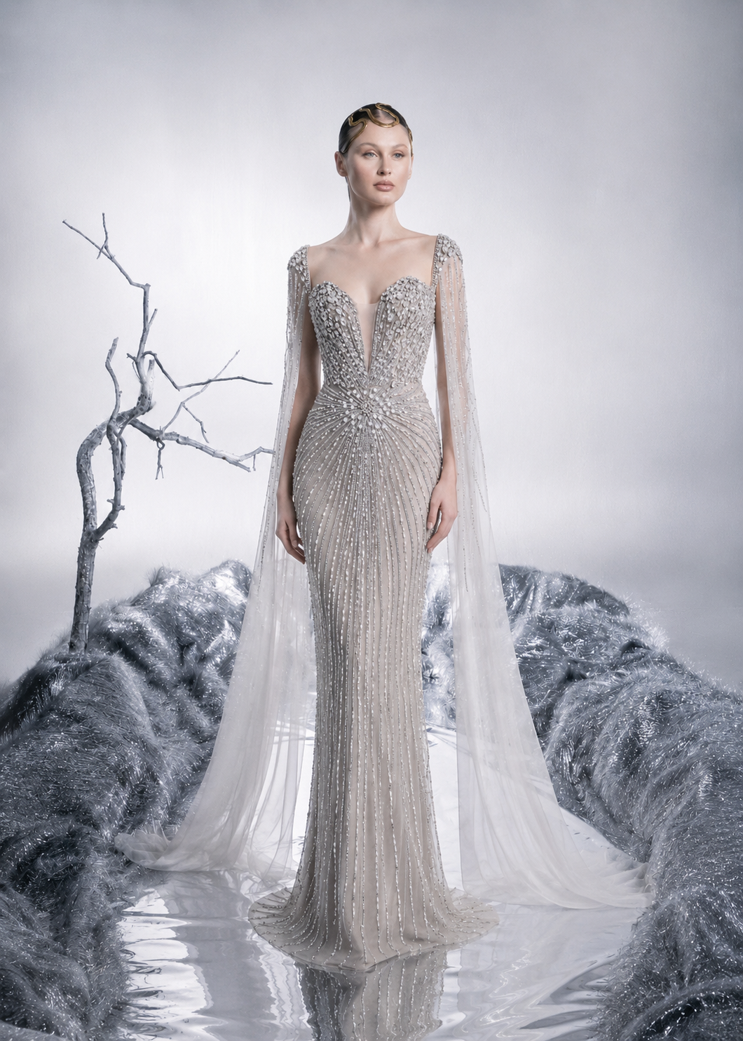 Woman in a silver beaded gown with a cape against a snowy landscape background